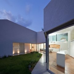 Courtyard With White Kitchen Table Viewed Through Glazed Wall In Green - Karbonix