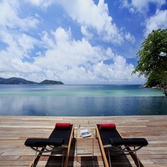 On Black Lounge Chairs With Small Table Overlooking Blue View Red Towels - Karbonix